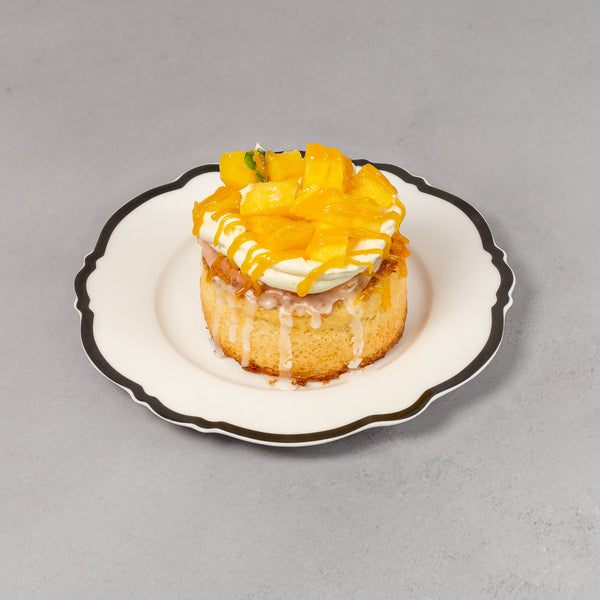 Small dessert with yellow topping on a decorative plate against a gray background