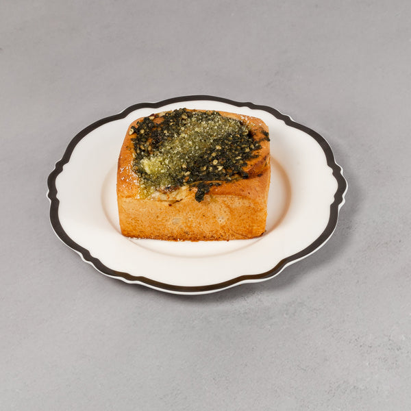 Small dish with a piece of bread topped with green herb on a gray background