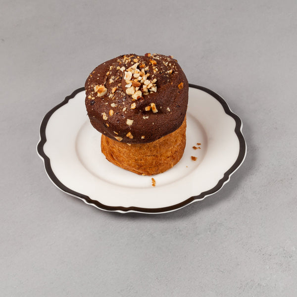 Small dessert with chocolate topping on a white plate against a gray background