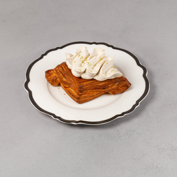 Small dessert with whipped cream on a white plate against a gray background
