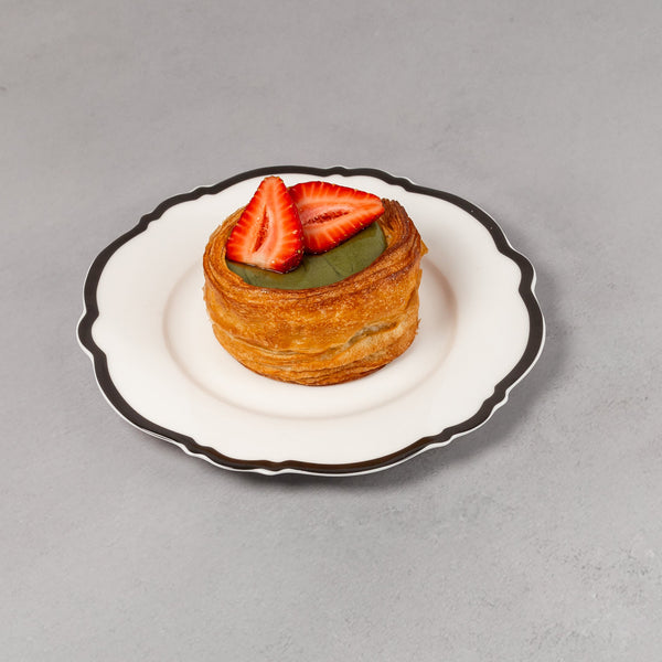 Small pastry with strawberries on a white plate against a gray background