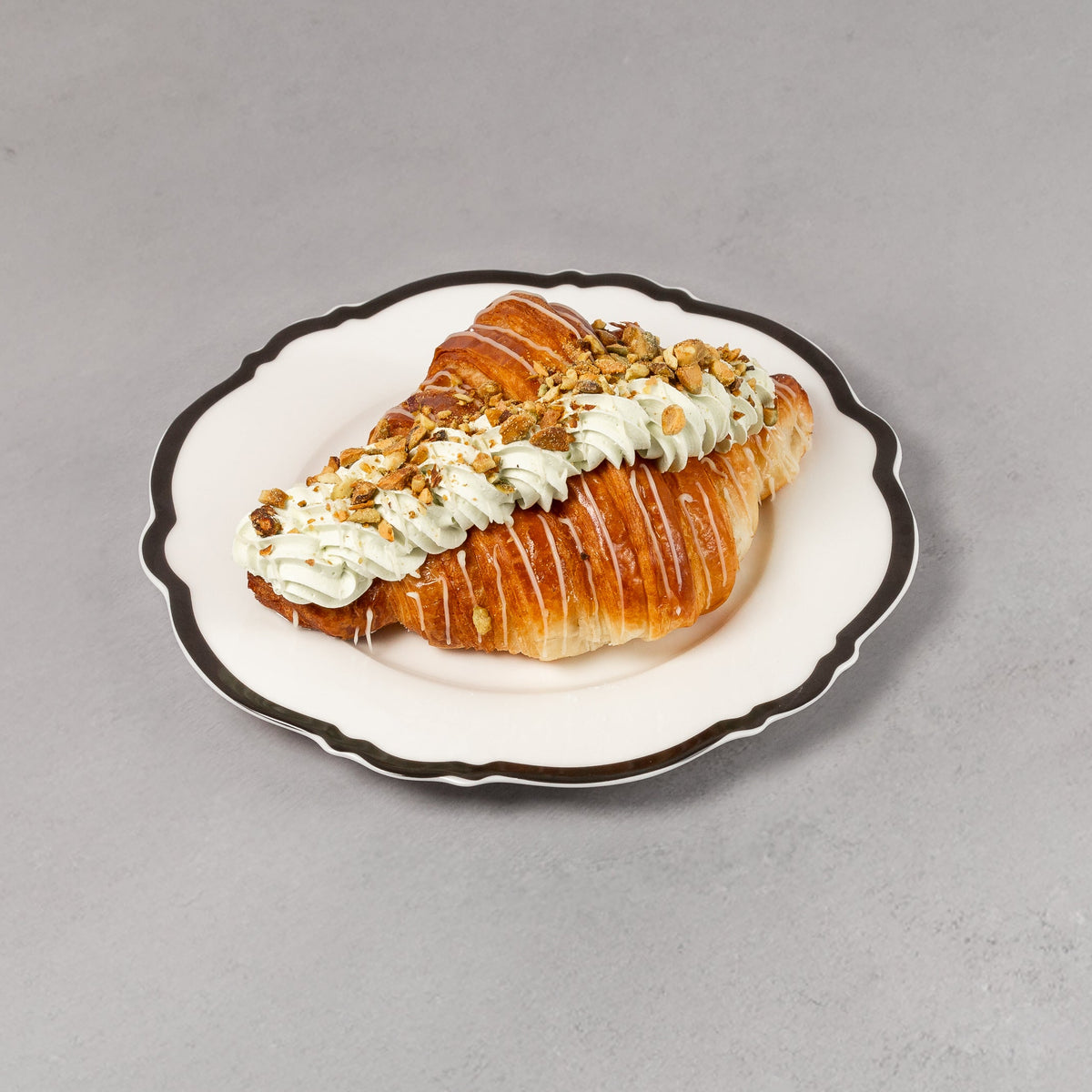 Pastry with cream on a decorative plate against a gray background