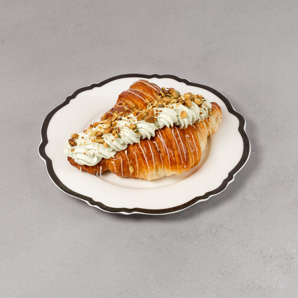 Pastry with cream on a decorative plate against a gray background
