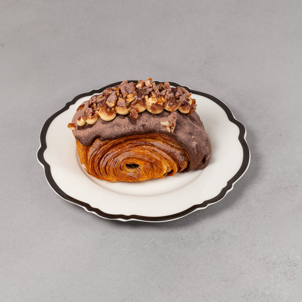 Pastries on a small white plate with black rim on a gray background